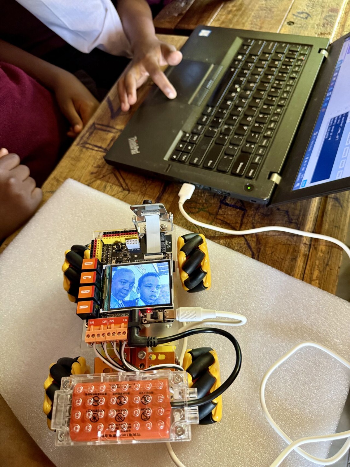 Codewalk robotic car connected to a laptop displaying students during a robotics session